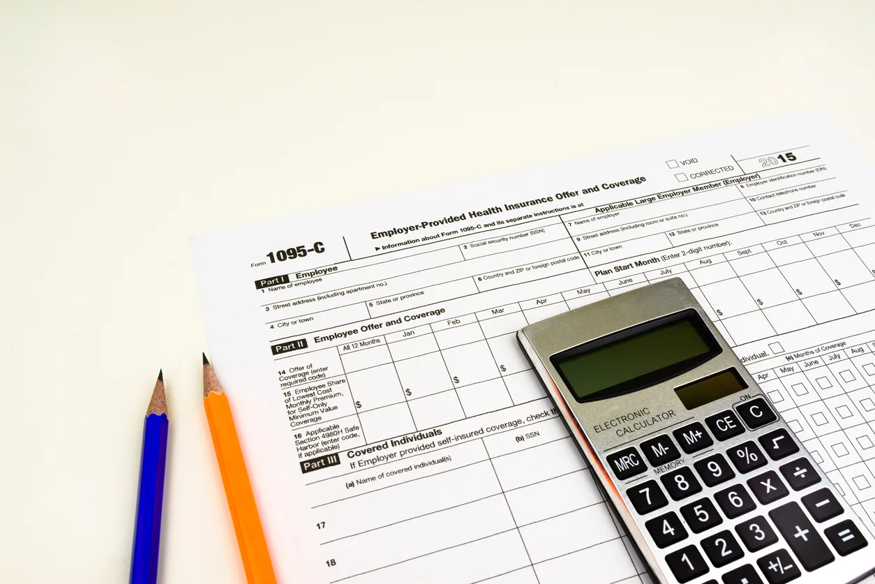 Tax professional reviewing Form 1095-C ACA employer reporting documents at a desk