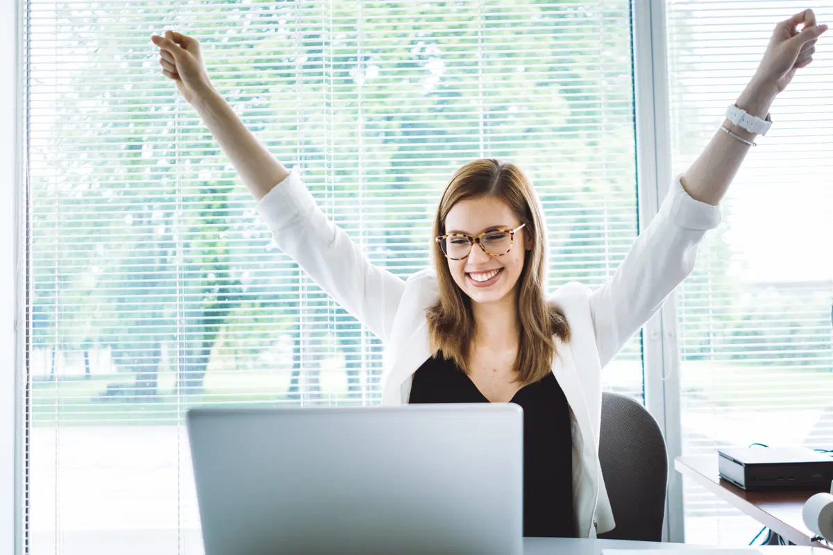 Businesswoman celebrating at computer — benefits enrollment milestone achievement