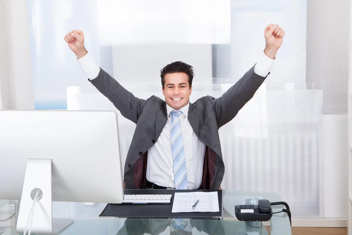 Businessman at desk celebrating — successful open enrollment period completion